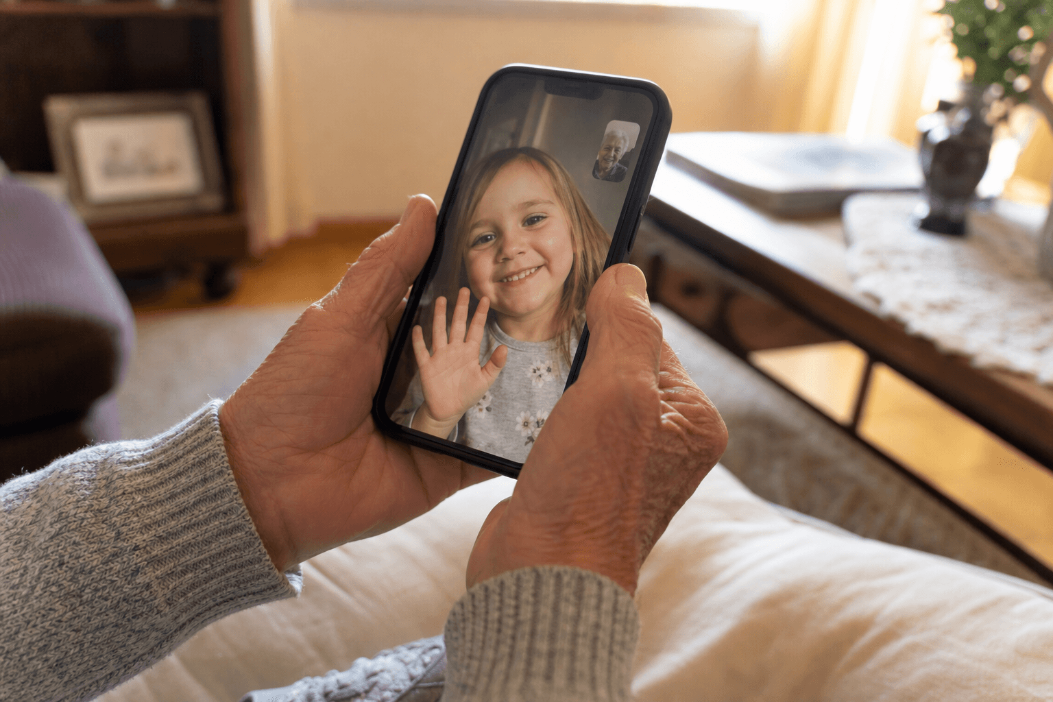 Older hands holding a phone showing a grandchild